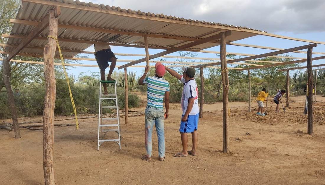 Volunteers raising the roof frame of a new community building on open ground in La Guajira, Colombia.
